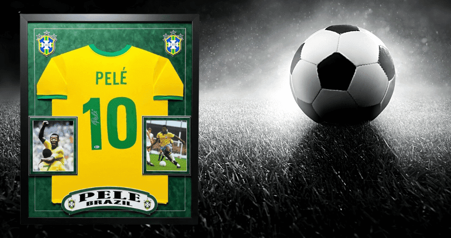 Click this button to shop Inscriptagraphs' Soccer Memorabilia Collection! Pictured in the graphic is a framed Pele Brazil jersey on top of a black and white graphic of a soccer field with a soccer ball shown and displayed on the grass.
